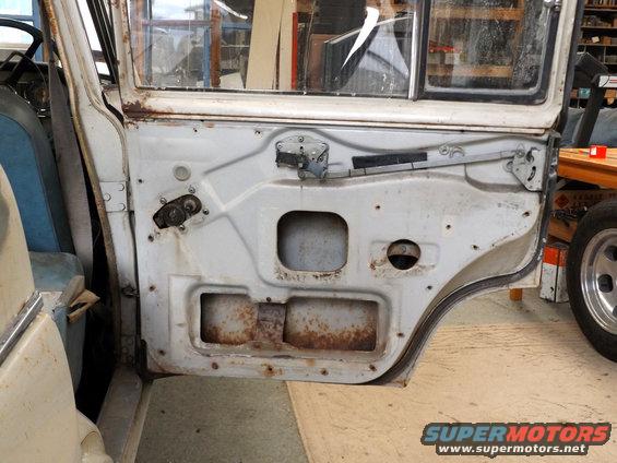 Interior of a white car door showing rust and exposed metalwork, with visible window mechanism and door latch