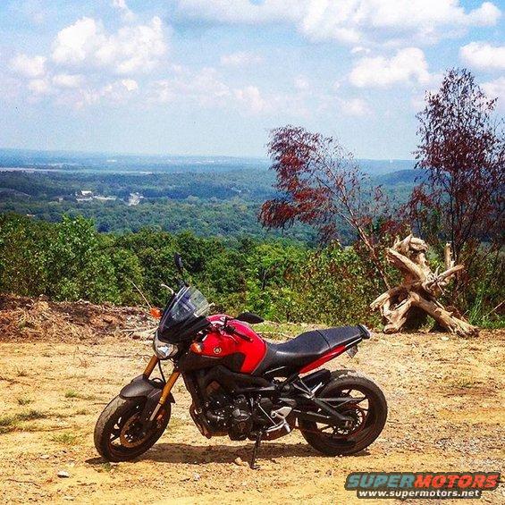 Red Yamaha motorcycle parked on dirt with a scenic overlook