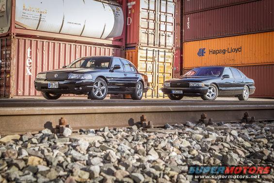 Black Mercury Marauder and a black Chevrolet Impala parked side-by-side on train tracks