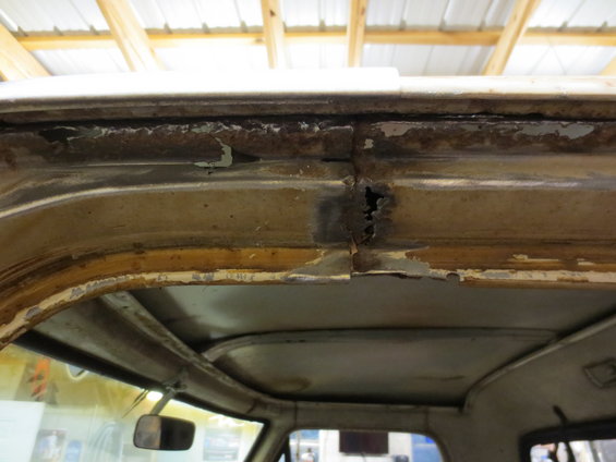 rusted seam on the roof of a vehicle, showing peeling paint and holes
