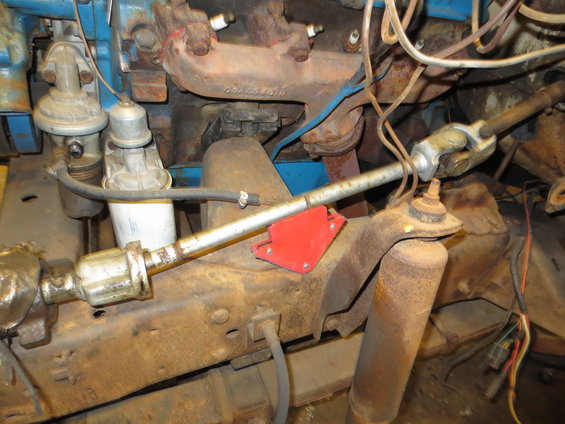 Close-up of rusty steering linkage, shock absorber, and engine components