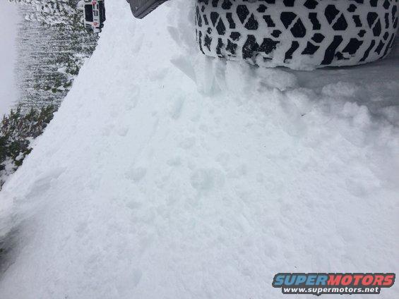 Jeep Wrangler in snow, tire visible. Another vehicle in background