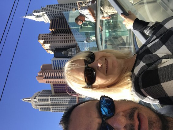 Two people in sunglasses with a cityscape behind them