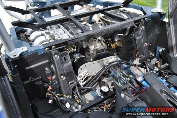 Engine compartment with exposed engine, wiring, and a gauge