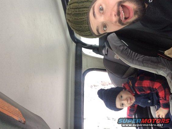 Man and child in car interior, child in car seat. Snow visible outside