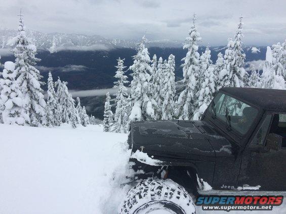 Black Jeep in snow, front fender and tire visible, with Supermotors logo on lower door