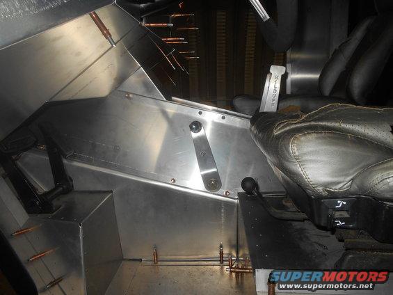 Vehicle interior with brushed metal panels, black leather seat, and floor shifter