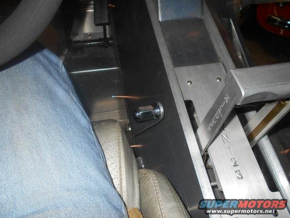 Close-up of a vehicle's interior showing a custom shifter mechanism and part of a driver's leg in jeans