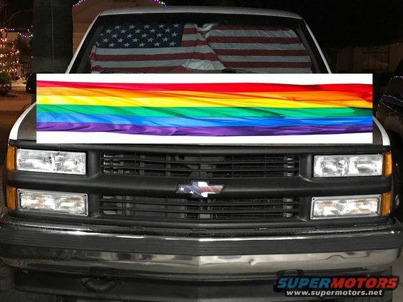 Front of a truck with a rainbow flag sticker and American flag sunshade