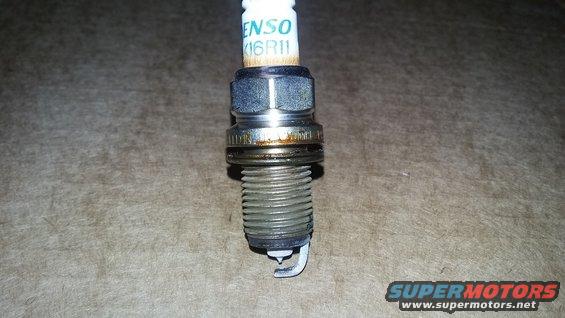 Spark plug with DENSO 16R11 text, showing wear and carbon buildup