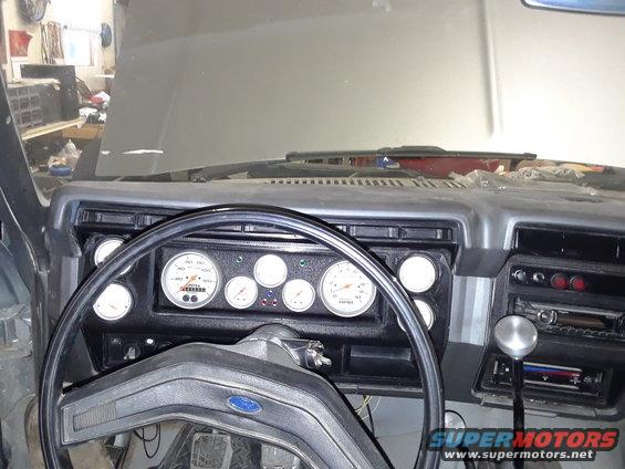 Interior view of a 1985 Ford Bronco's dashboard with custom gauges