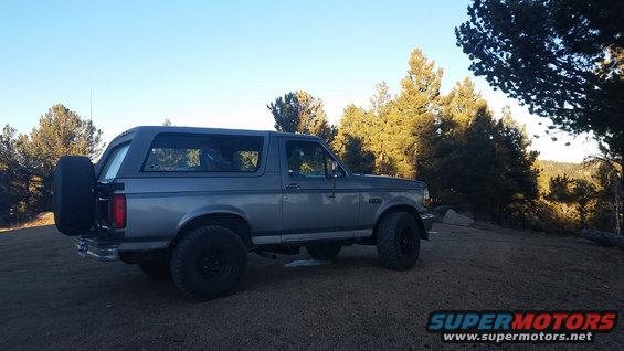 1995 Ford Bronco parked on dirt with trees in background
