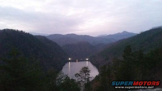Mountain valley with lake and lights at dusk