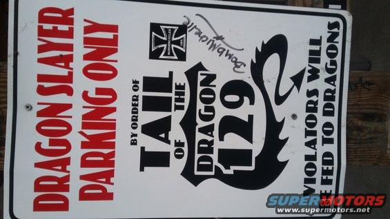 Sign reads 'DRAGON SLAYER PARKING ONLY' and 'BY ORDER OF THE TAIL OF THE DRAGON 129' and 'VIOLATORS WILL BE FED TO DRAGONS'