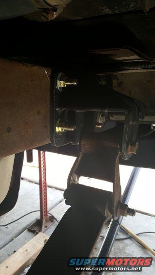 Close-up of a vehicle's leaf spring and a black metal suspension bracket with bolts