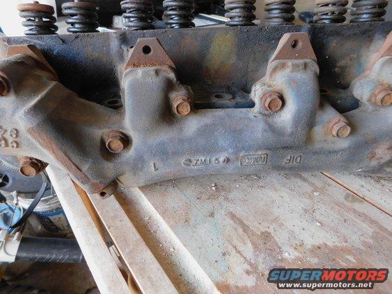 Close-up of an engine cylinder head with visible casting marks and bolts