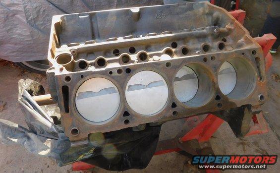 Engine block with three pistons visible, resting on red stands. Casting number '427' visible on top