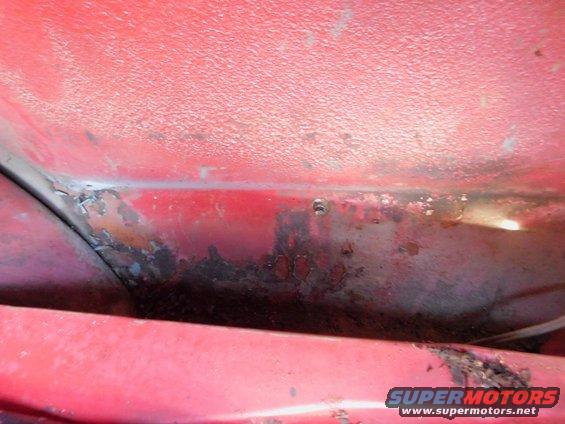 Close-up of red painted metal showing rust damage and peeling paint