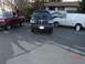 1995 Ford Bronco - A black 1995 Ford Bronco is parked on wet asphalt, with a red pickup truck and a white van nearby.