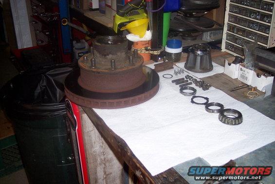 Front wheel hub and brake rotor assembly with bearings and bolts laid out on a workbench