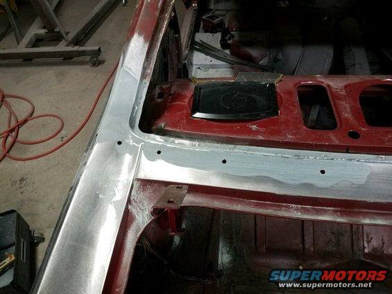 Red car interior with bare metal and primer on the A-pillar and roofline, showing repair work