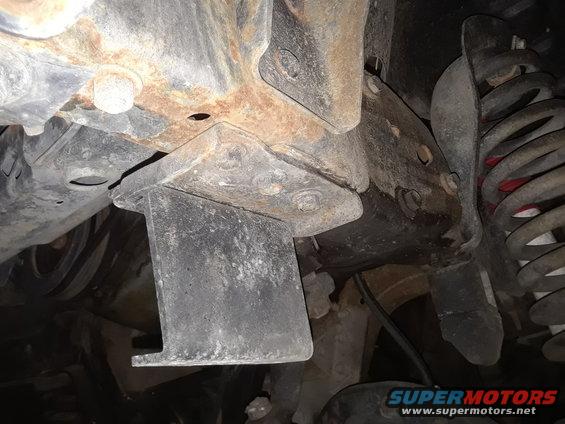 Undercarriage view of rusty frame and suspension components, with SuperMotors logo