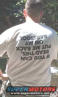 Man in white t-shirt with text: IF YOU CAN READ THIS, PUT ME BACK ON MY BARSTOOL. Supermotors logo at bottom