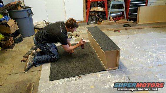 Man spraying a subwoofer box in a garage