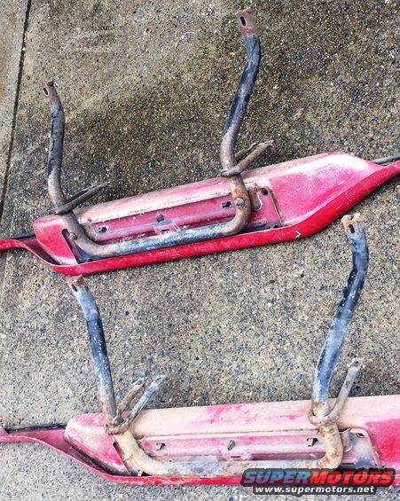 Two red vehicle body panels with black and rusted metal brackets.