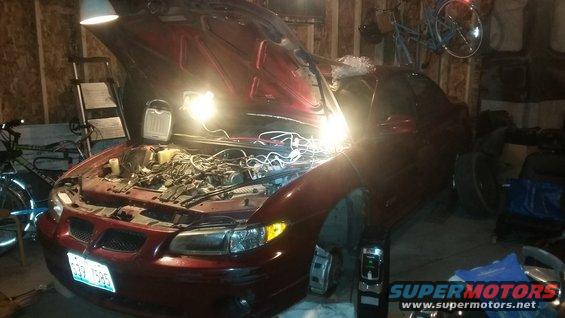 Red 2000 Pontiac Grand Prix with hood open, engine exposed, in a garage