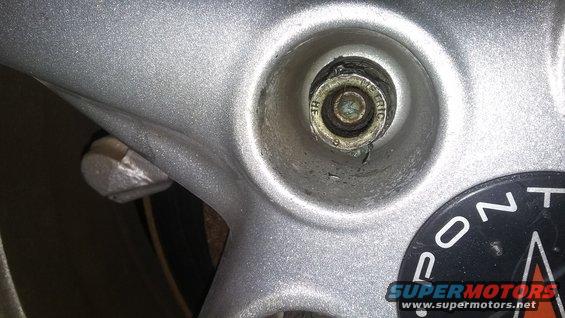 Close-up of a lug nut and part of a wheel with 'PONTIAC' visible