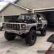 1979 Ford Bronco - A lifted 1979 Ford Bronco is parked in a driveway with its hood open, revealing the engine compartment.