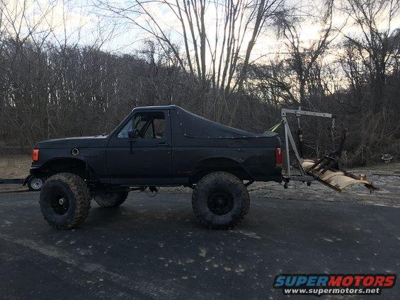 1989 Ford Bronco with large tires and a soft top, parked outdoors