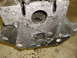 1969 Ford Mustang - Close-up view of a gray engine block with visible bolt holes and openings, resting on a concrete surface.