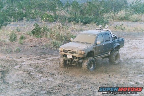 1990 Toyota Tacoma lifted truck driving through mud with large tires
