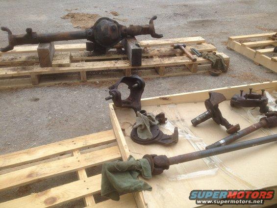 rusty vehicle axle and suspension parts laid out on wooden pallets