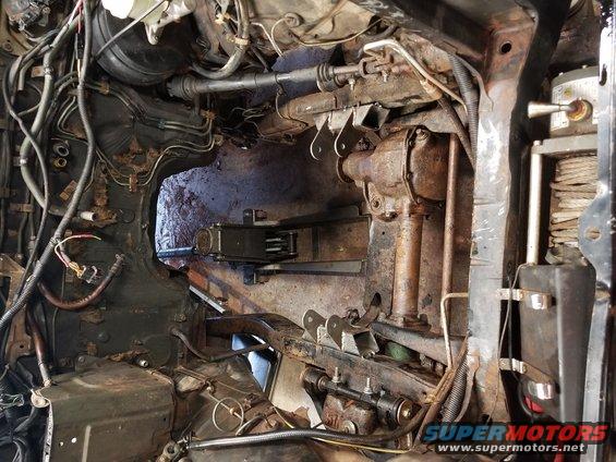 Undercarriage and engine bay of a vehicle, showing rusty components and wiring
