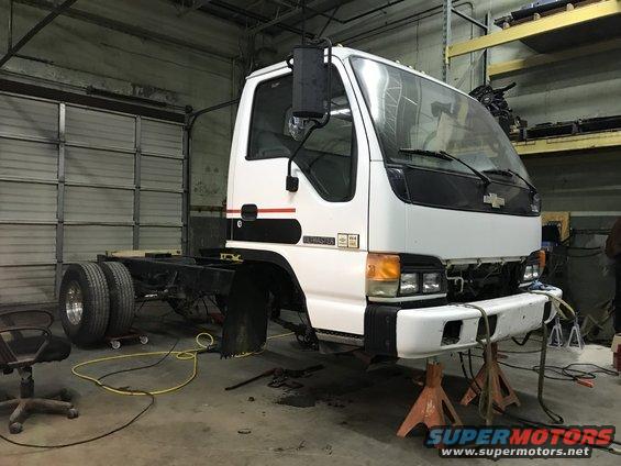 White truck chassis on jack stands with front end removed