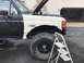 1989 Ford Bronco - This Ford F-250 appears to be undergoing repairs or modifications, with its hood open and a large off-road tire visible. A ladder is positi…