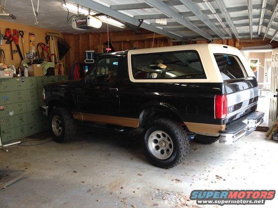 Black Ford Bronco with tan top parked in a garage