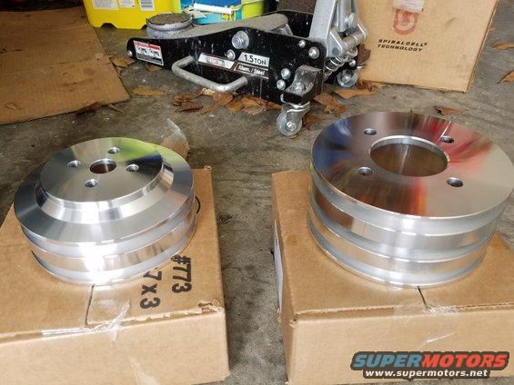 Two aluminum pulleys on cardboard boxes with a floor jack in the background