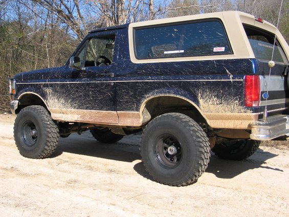 1995 Ford Bronco side view, covered in mud, with large tires