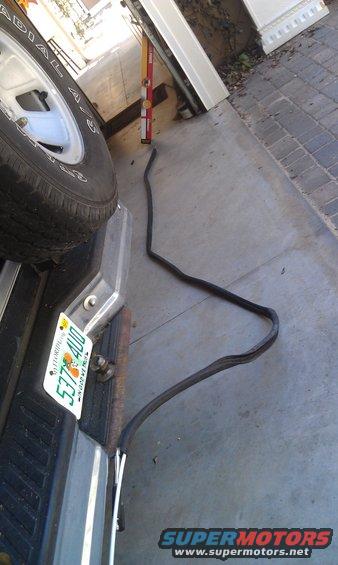 Rubber seal lying on concrete next to a spare tire and license plate