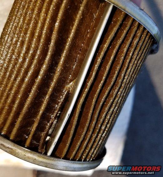 Close-up of a used oil filter with dirty, pleated filter media