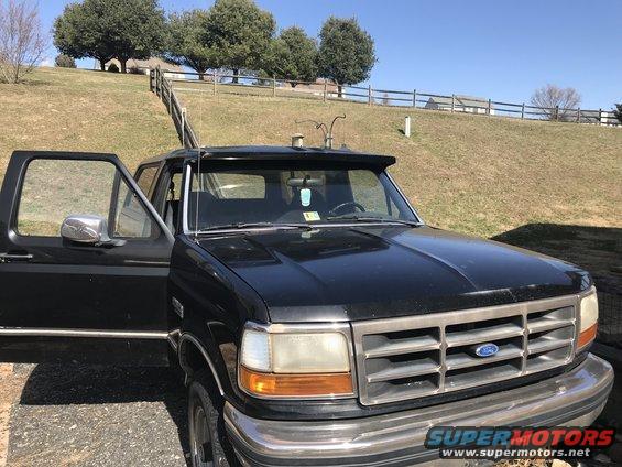 Black 1992 Ford Bronco with driver's door open, parked outside on a sunny day