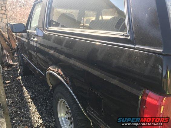Black SUV parked outside, showing rust around the rear wheel well and a partial view of the interior