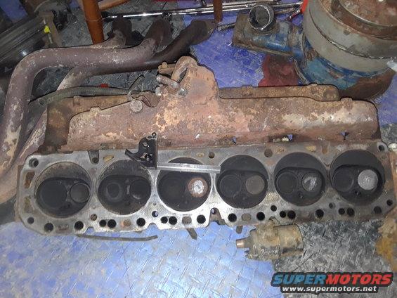 engine cylinder head with exhaust manifold attached, appears rusty