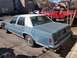 1987 Ford Crown Victoria LTD - A blue sedan with a white roof is parked next to a red truck.
