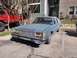 1987 Ford Crown Victoria LTD - This 1987 Ford Crown Victoria LTD is seen from the front-right in a parking lot. A red off-road vehicle is parked to its left.