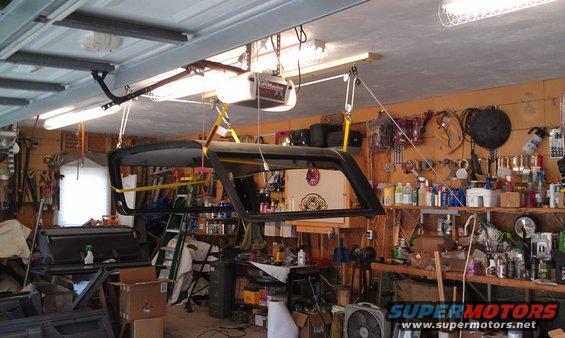 hardtop removed from vehicle and suspended by hoist in garage